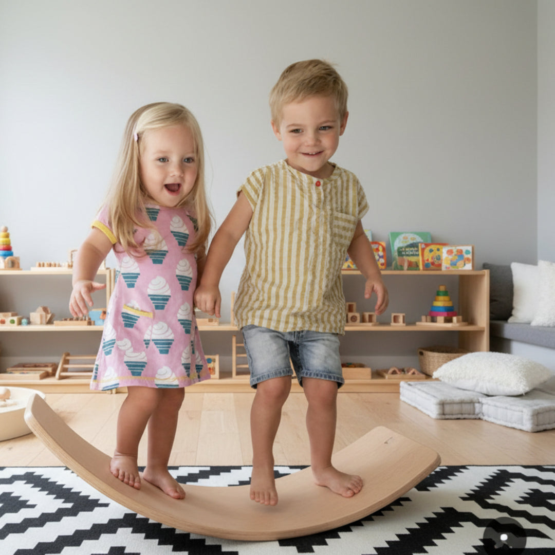 Two children standing on a wooden balance board in a room with toys and furniture.